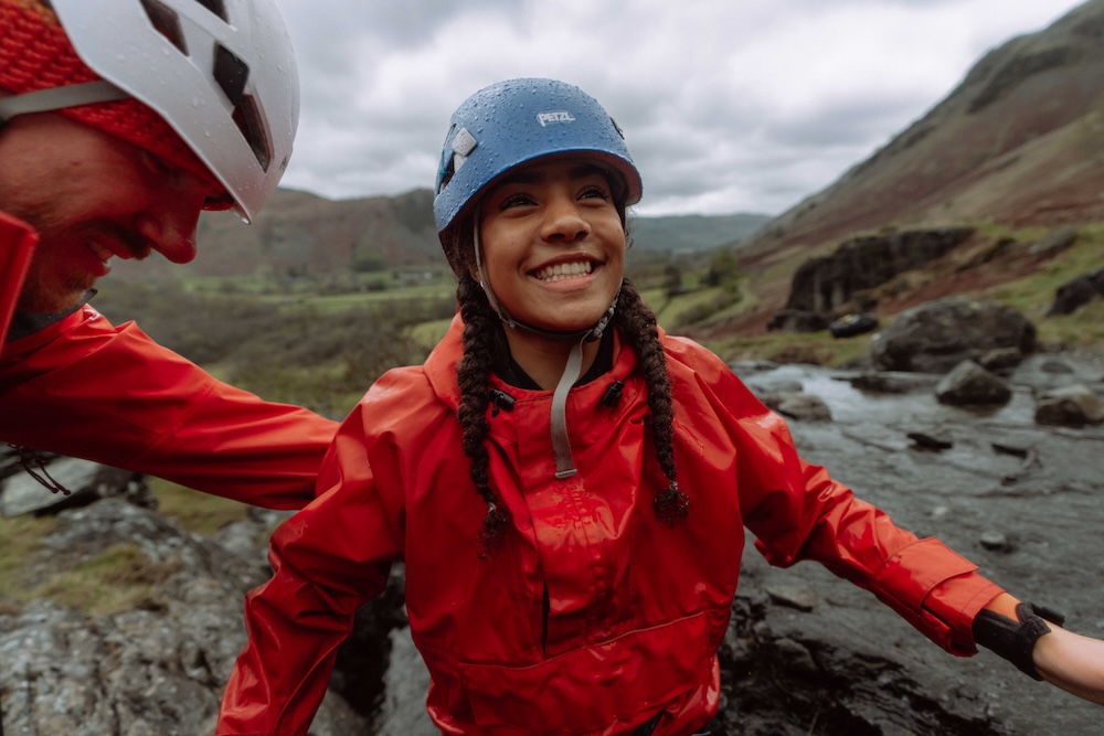 A lady dressed in outdoor gear including a helmet and smiling