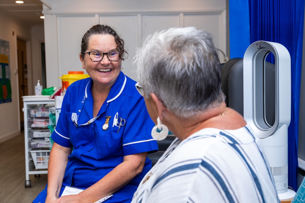 a hospice nurse talking to a patient in a bed